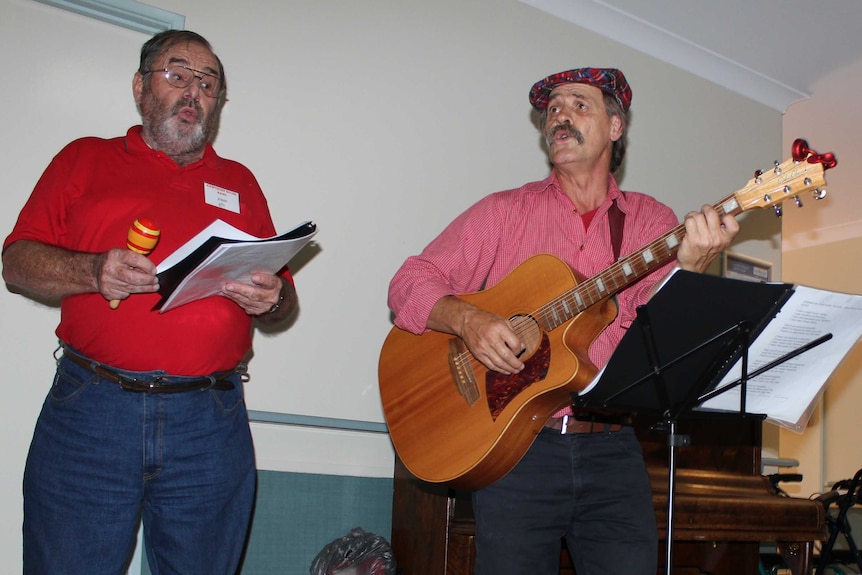 Two men stand and sing.