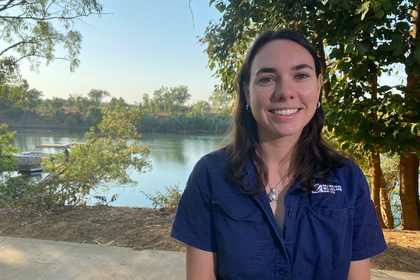 A smiling woman with brown hair and a deep blue Parks and Wildlife shirt on