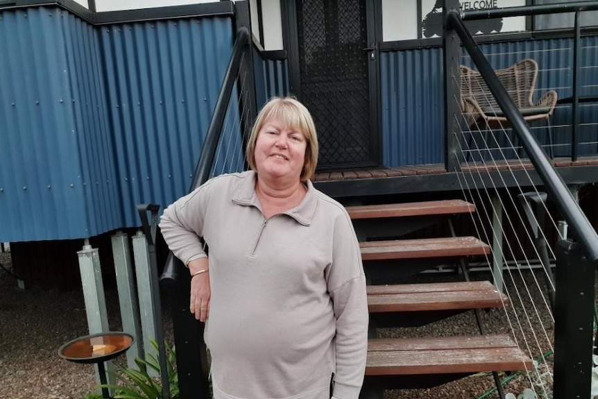 Une femme photographiée à la maison appuyée contre une balustrade