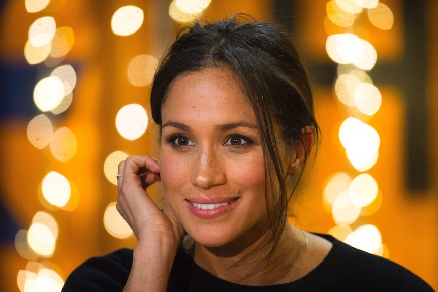 Tight shot of Meghan Markle smiling and looking past the camera.