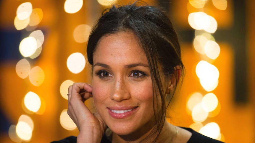 Tight shot of Meghan Markle smiling and looking past the camera.