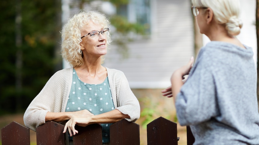 Two older women neighbours talking over the fence