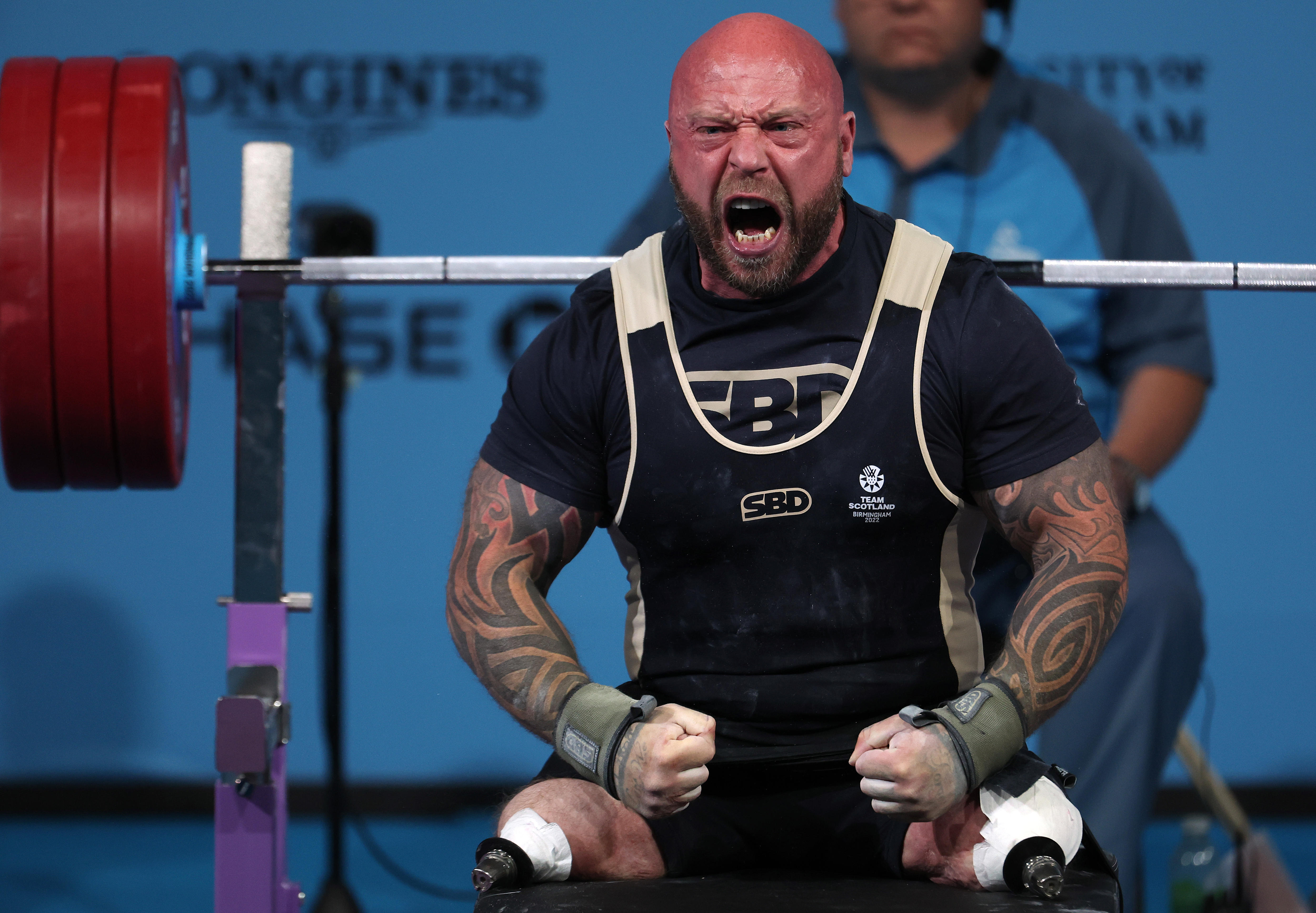 A man wearing black and white yells during a weightlifting competition