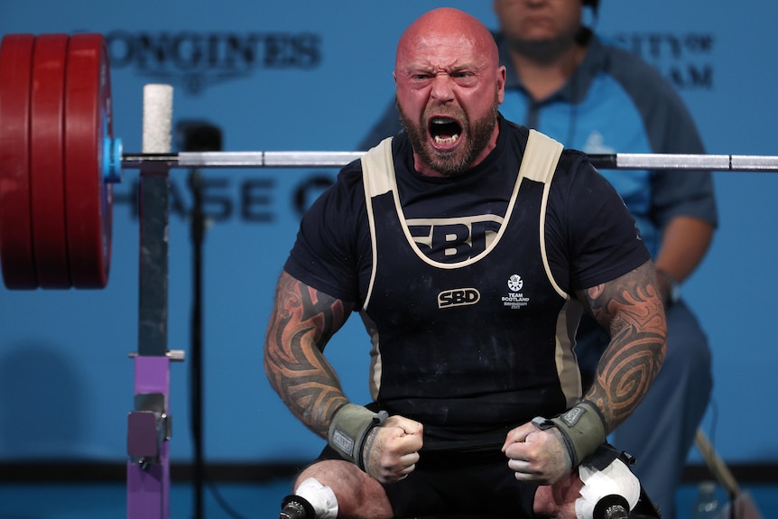 A man wearing black and white yells during a weightlifting competition