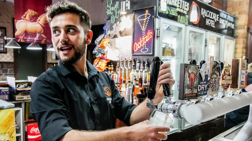 A bartender pours a pint in a pub. 
