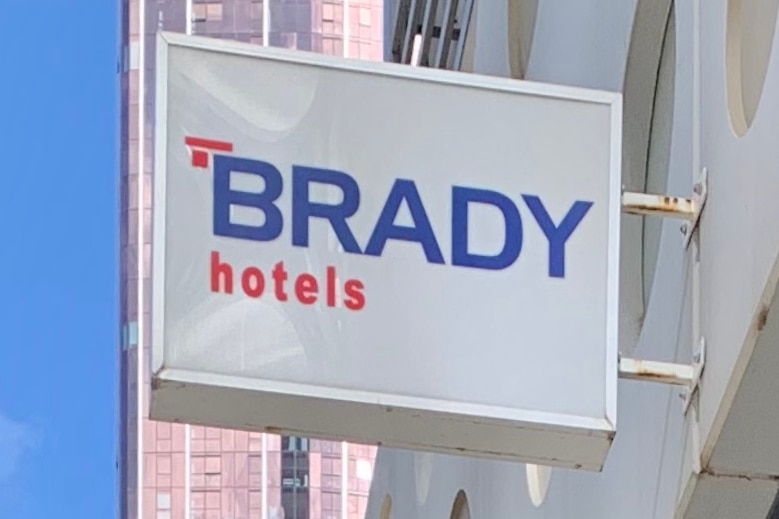 A sign reading 'Brady hotels' outside a hotel building in Melbourne on a blue sunny day.
