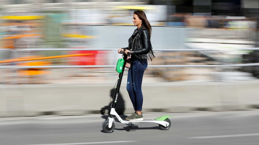 A woman rides a Lime e-scooter.