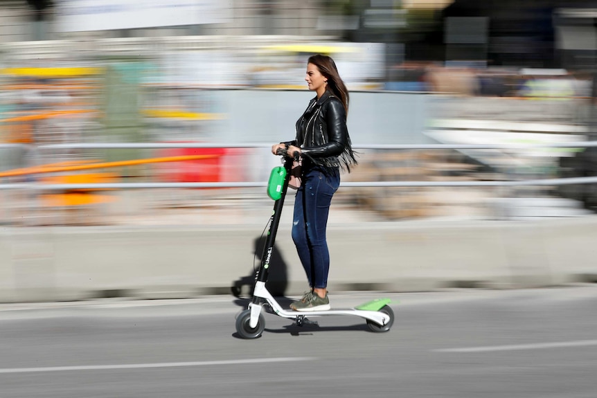 A woman rides a Lime e-scooter.