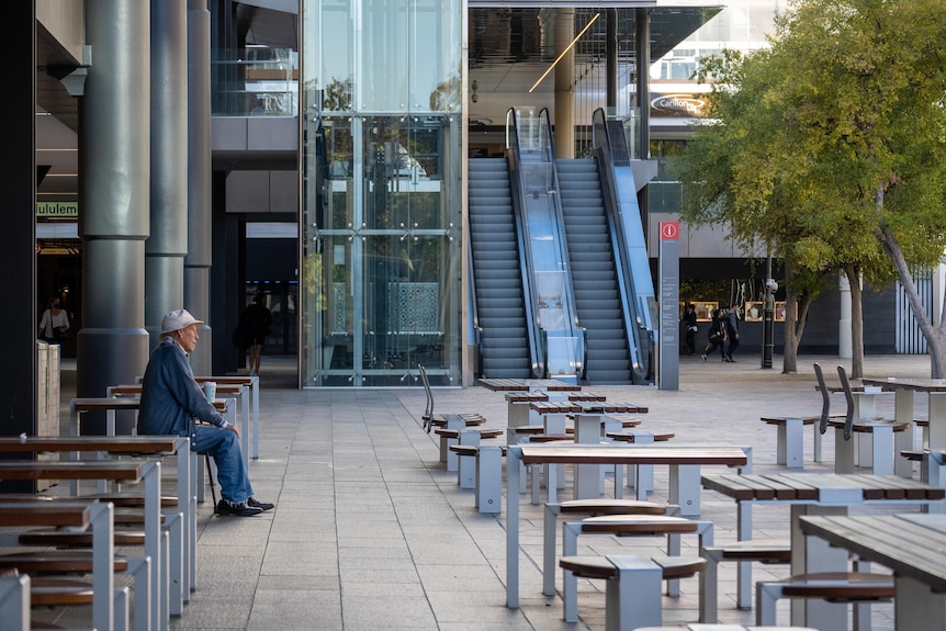 A man sits alone among empty seats in a public space