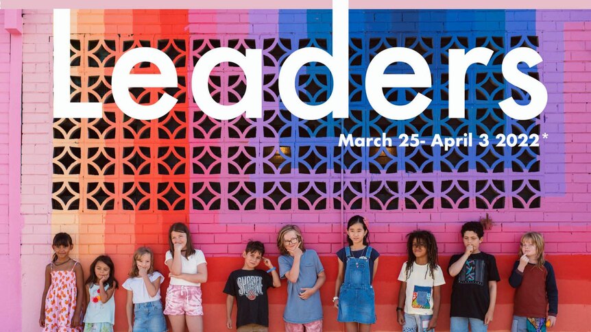 A row of primary age children against a multicoloured brick wall wondering about leadership.