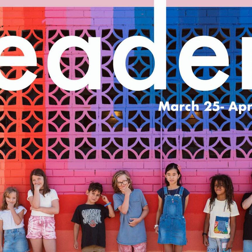 A row of primary age children against a multicoloured brick wall wondering about leadership.