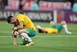 Football players lie on the ground looking devastated at a loss.