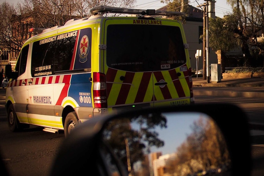 A Victorian ambulance as seen from a car window, reflected in the wing mirror.