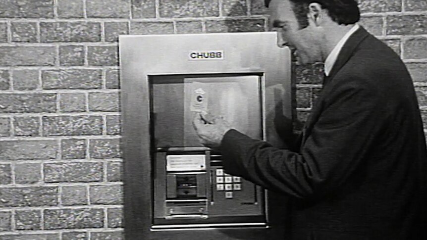 ABC reporter holds ATM card up at protoype machine in wall