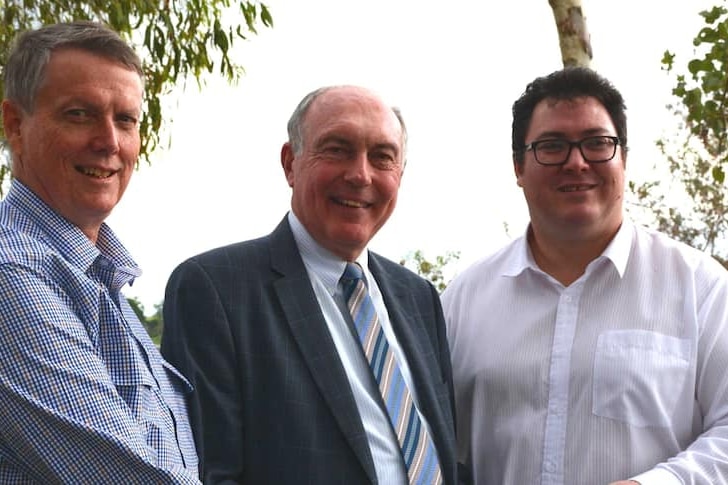 Three men in shirts and ties smiling for the camera.