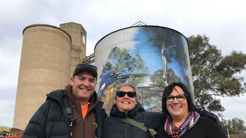 The artist Jimmy DVate stands with his wife, Carmen, and Rochester woman Kate Taylor. The mural towers behind them.