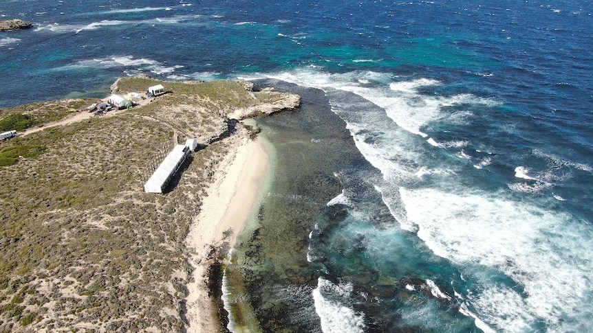 Une photographie aérienne par drone de Strickland Bay sur l'île de Rottnest, avec des dunes de sable et un océan bleu.