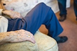 The hand of an elderly man sitting in an armchair in a nursing home.