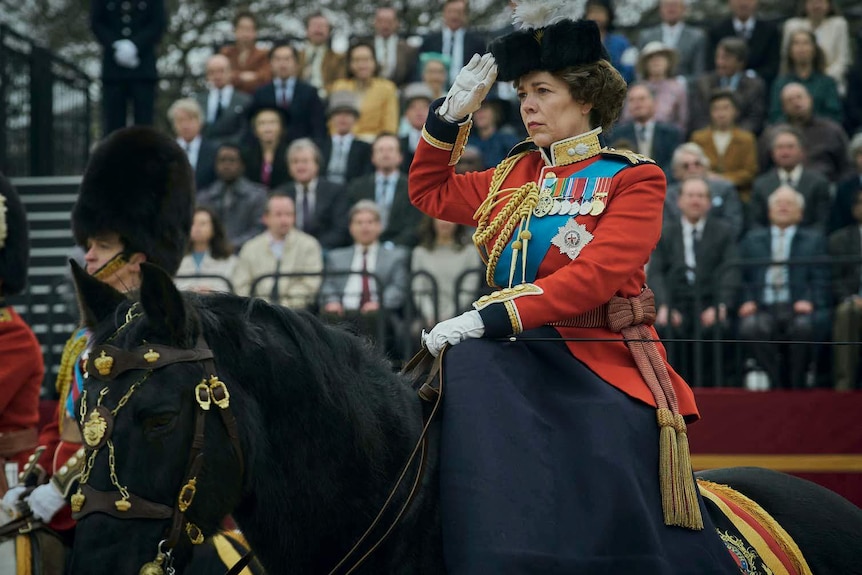 An actress playing Queen Elizabeth salutes from atop a horse
