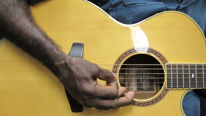 A man's arm is shown playing a guitar
