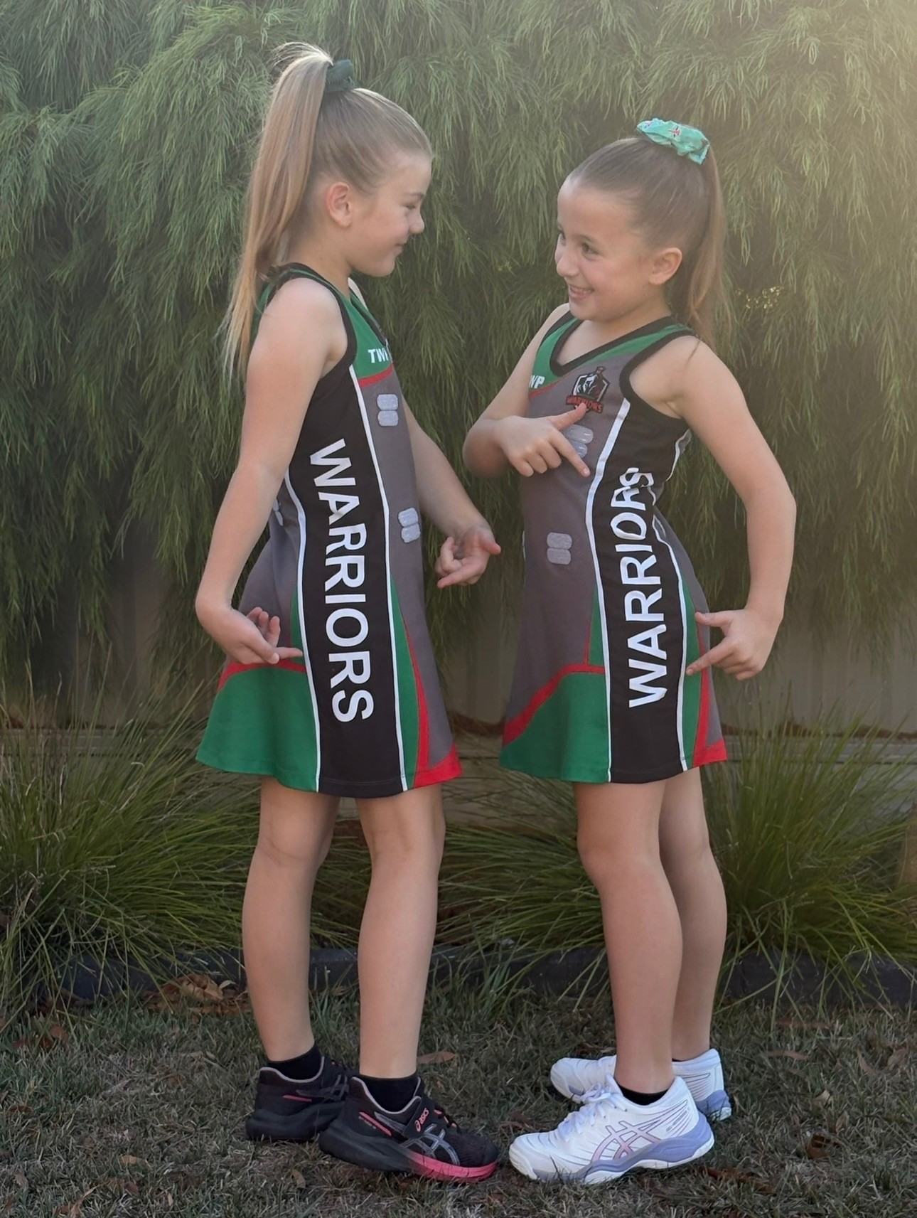 two little netballers in their dresses smiling 