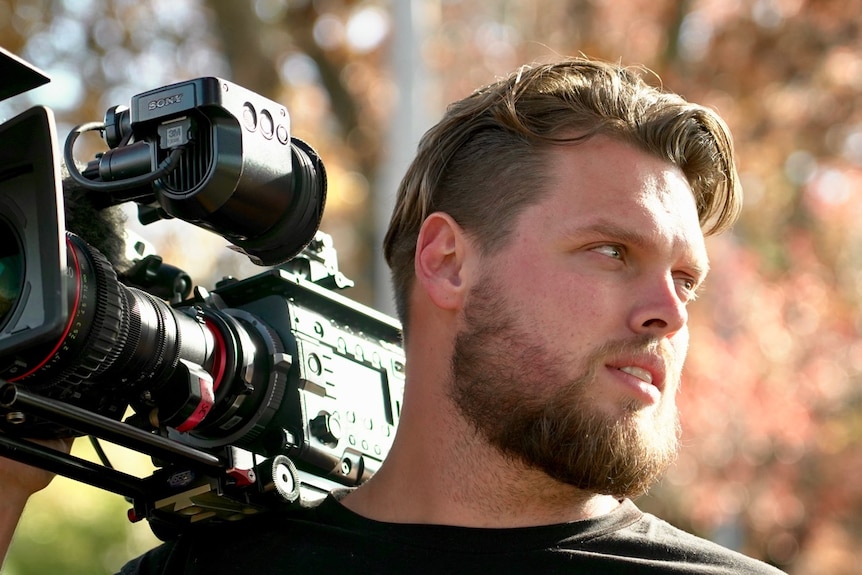 A young man holding a film camera.