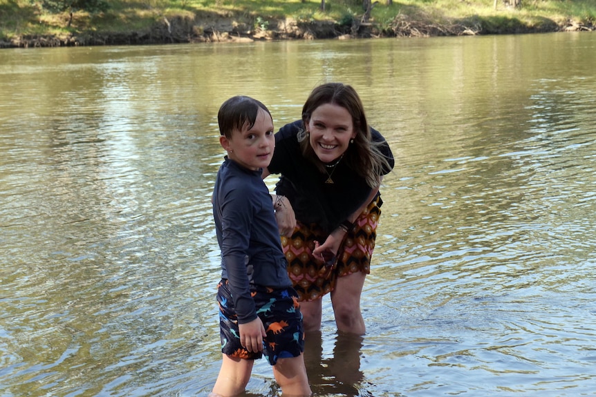 Leah Wiseman and her son Mac both stand in a river
