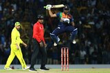 A Sri Lankan batsman leaps in the air in celebration as the umpire and an Australian player watch on.