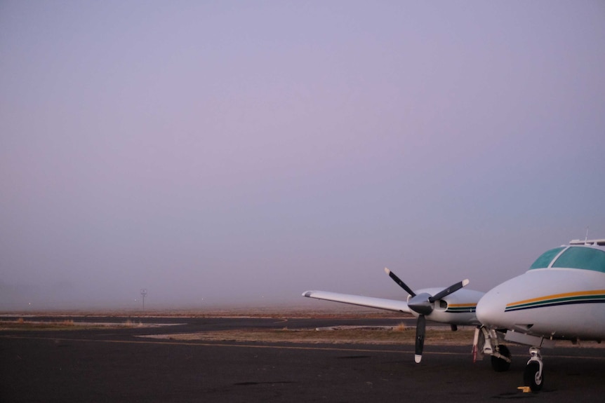 A plane sits on a regional airport at dusk.