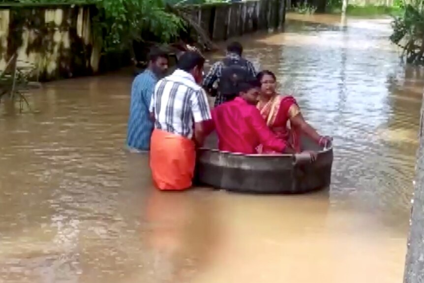 A couple in India in a floating tyre through floodwaters.