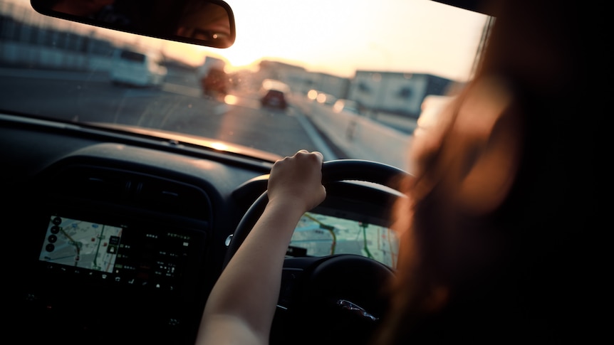 Woman driving a car, urban road in front of her