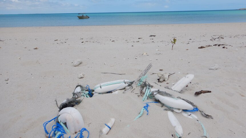 Some plastic bottles and other marine rubbish strewn on a sandy beach