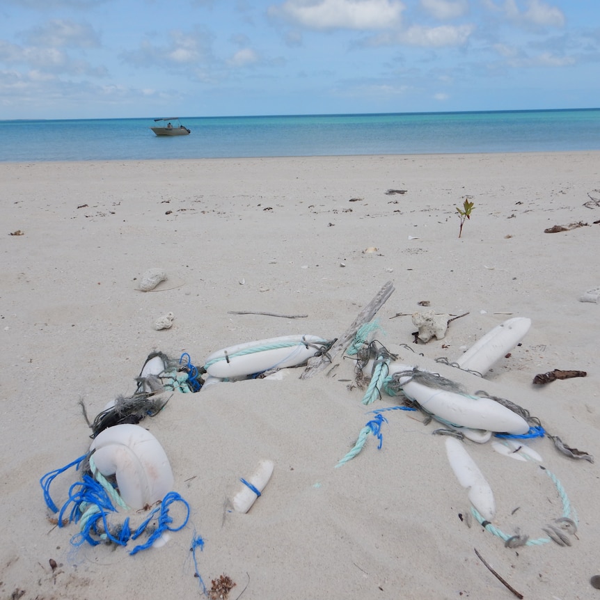 Some plastic bottles and other marine rubbish strewn on a sandy beach