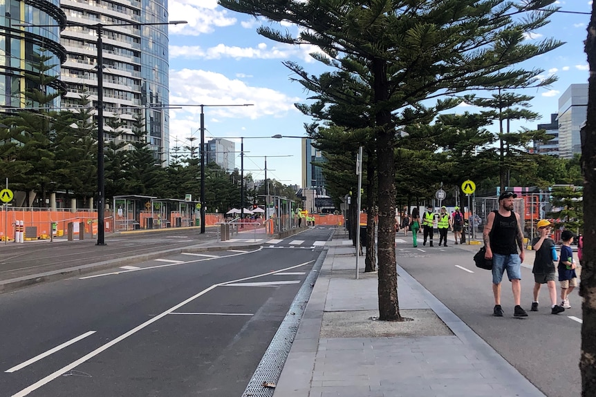 Une rue vide est barricadée alors que les gens marchent le long d'un sentier dans les Docklands de Melbourne
