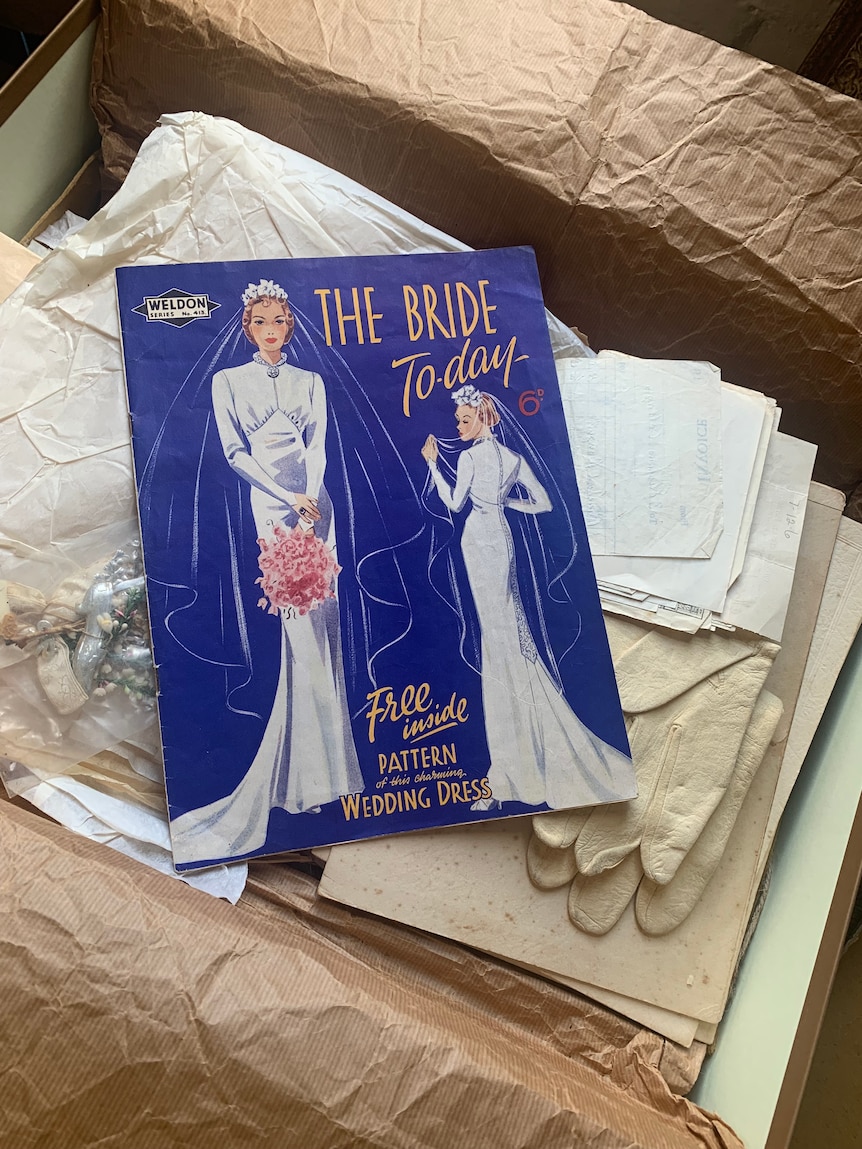 A magazine with a blue cover, titled, The Bride Today, lies in box lined with crumpled brown paper.