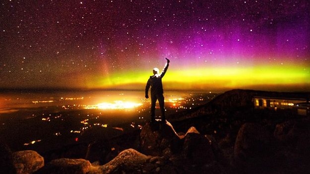 Purple and yellow lights on the horizon from the top of a mountain.