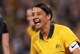 Sam Kerr smiles and clenches her fists by her sides