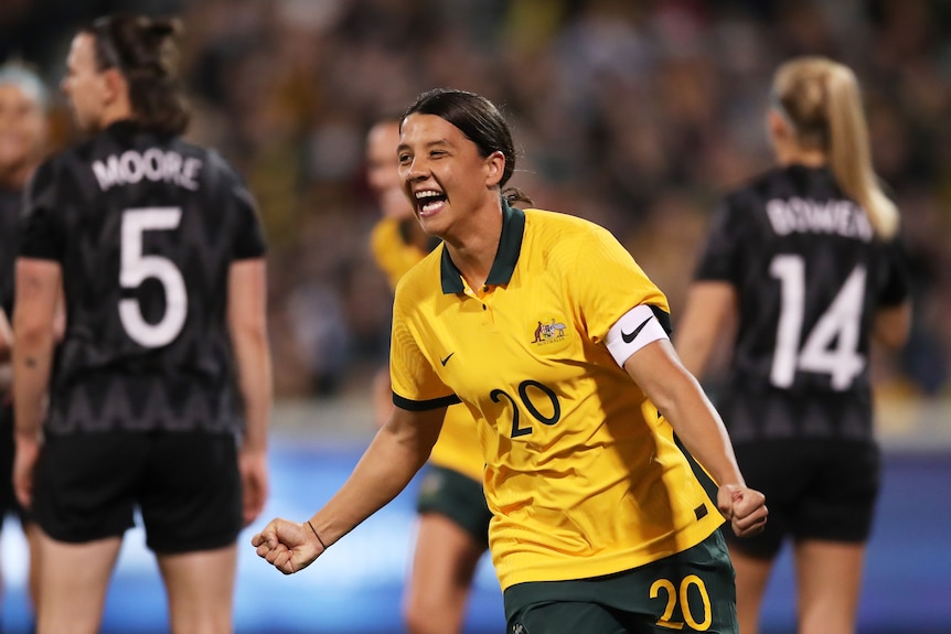 Sam Kerr smiles and clenches her fists by her sides