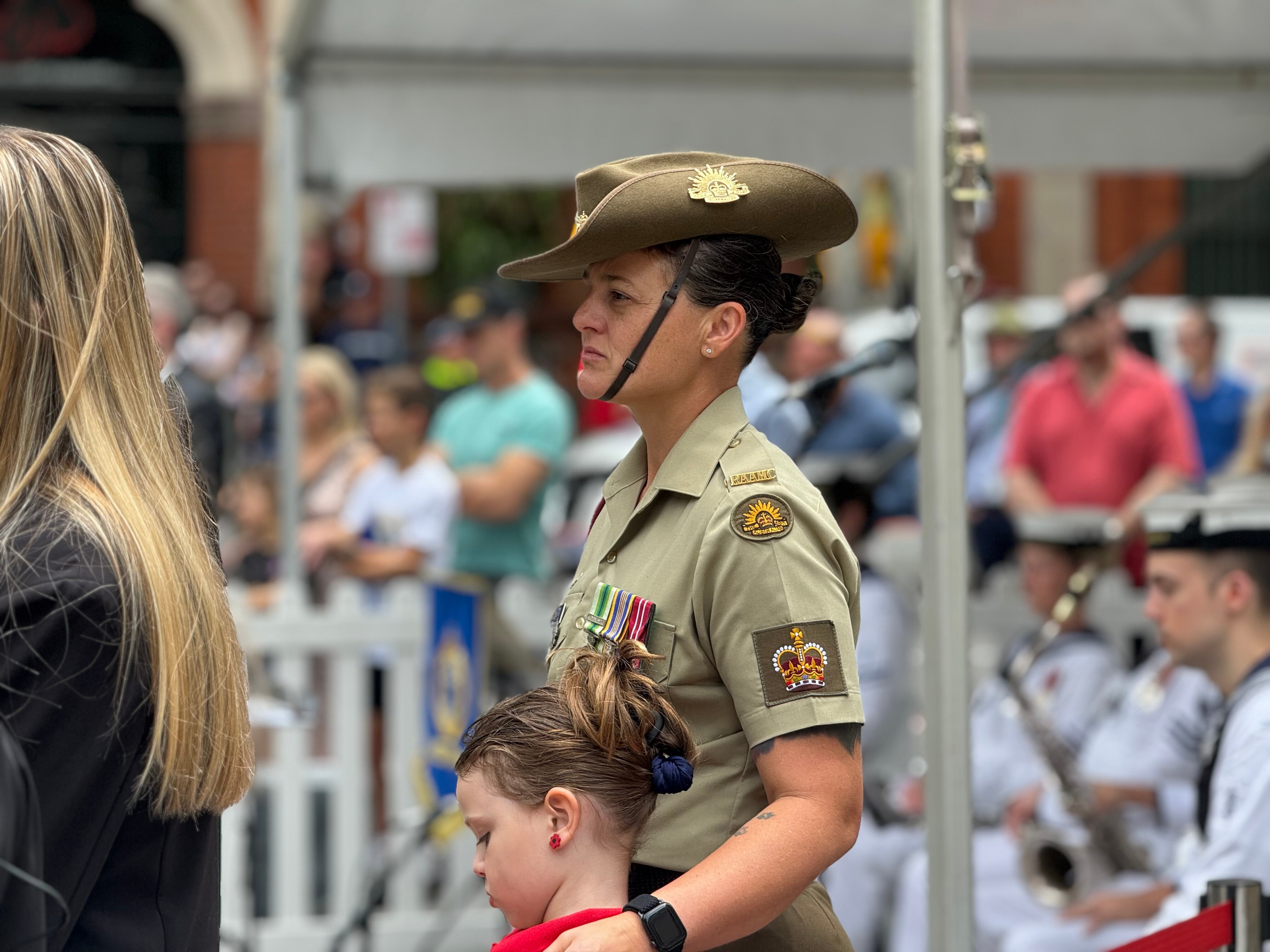 A servicewoman in uniform stands with a young girl.