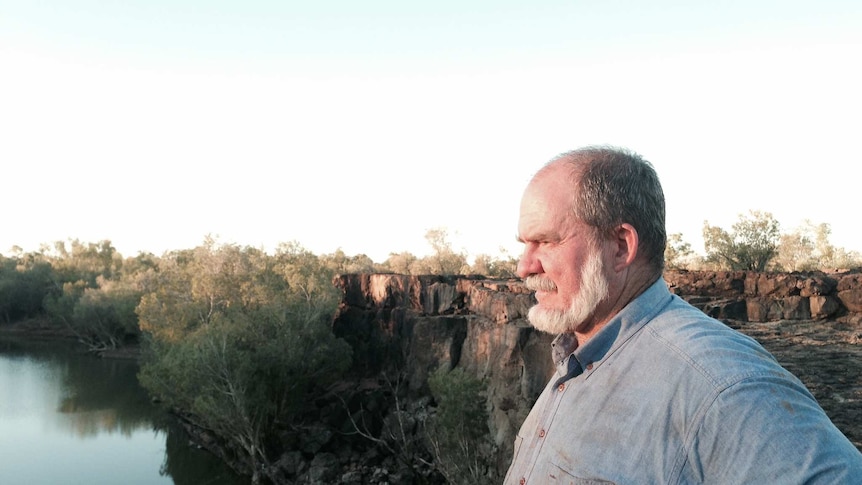 Burke shire Mayor Ernie Camp standing on the edge of a waterfall on his property in outback Queensland