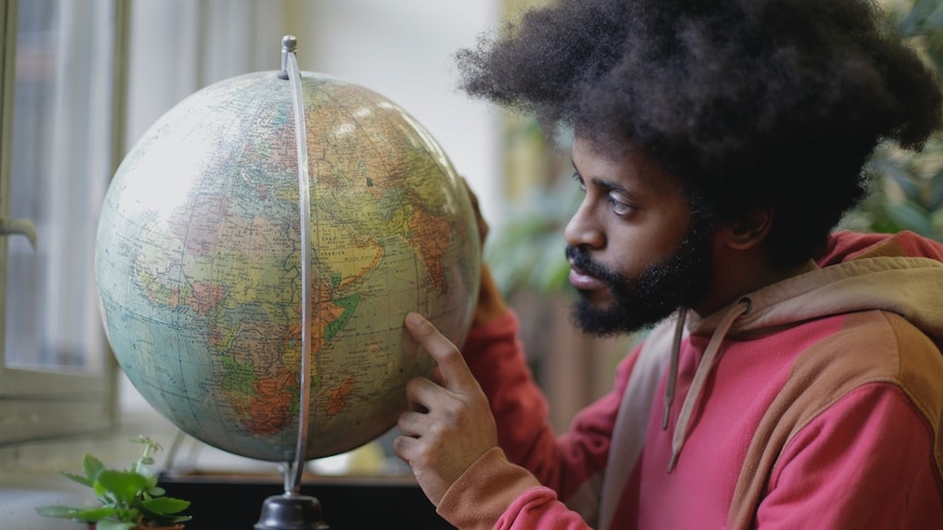 A man points at a world globe