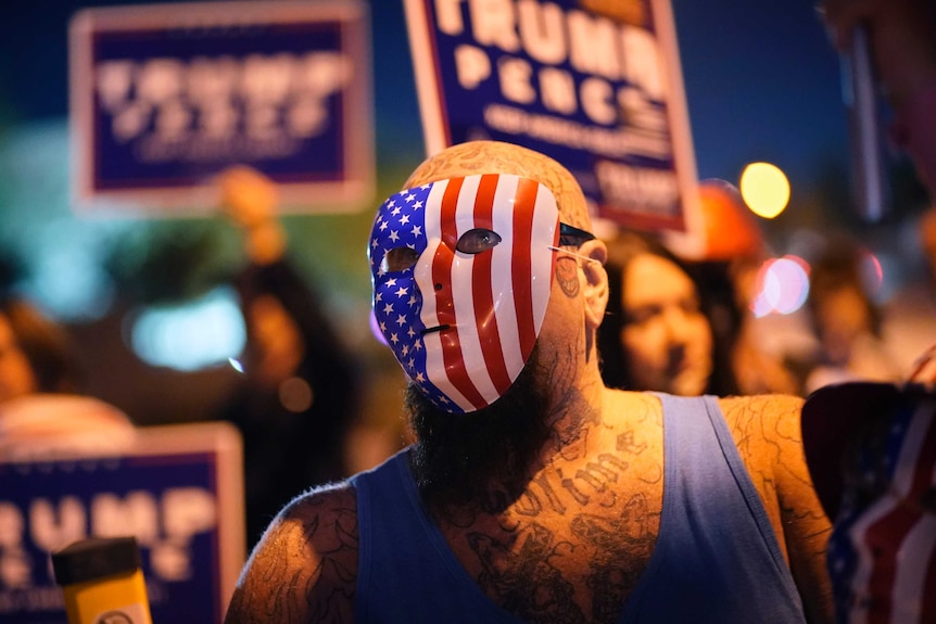 A Donald Trump supporter wears a United States flag themed hockey mask at a protest