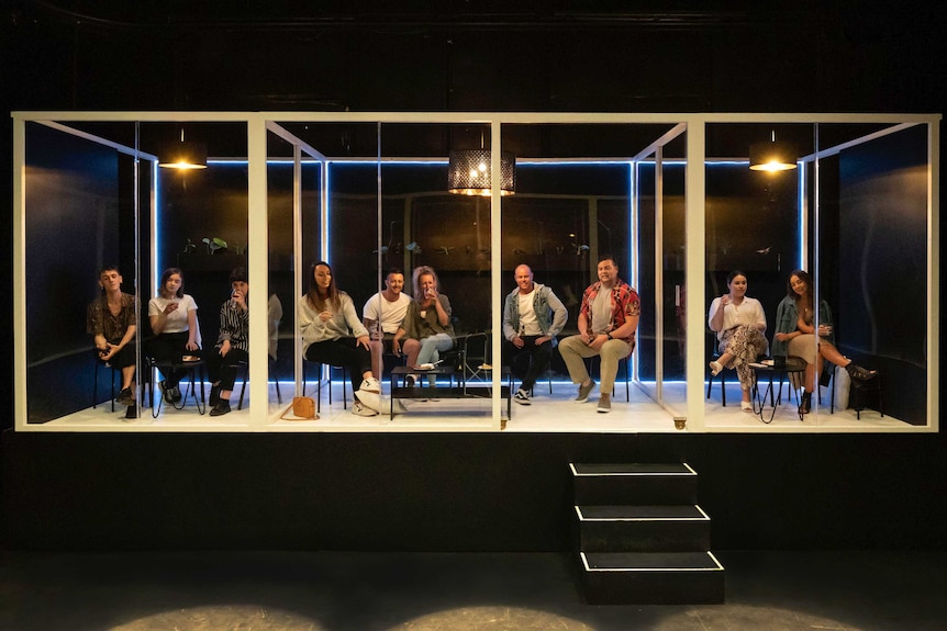 people sitting in glass pods watching theatre