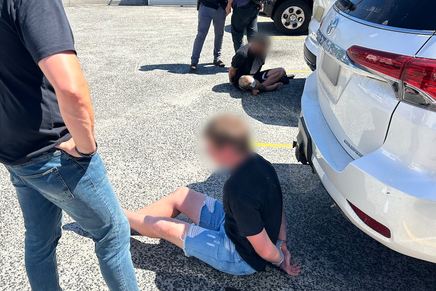 Two men on the ground being arrested.