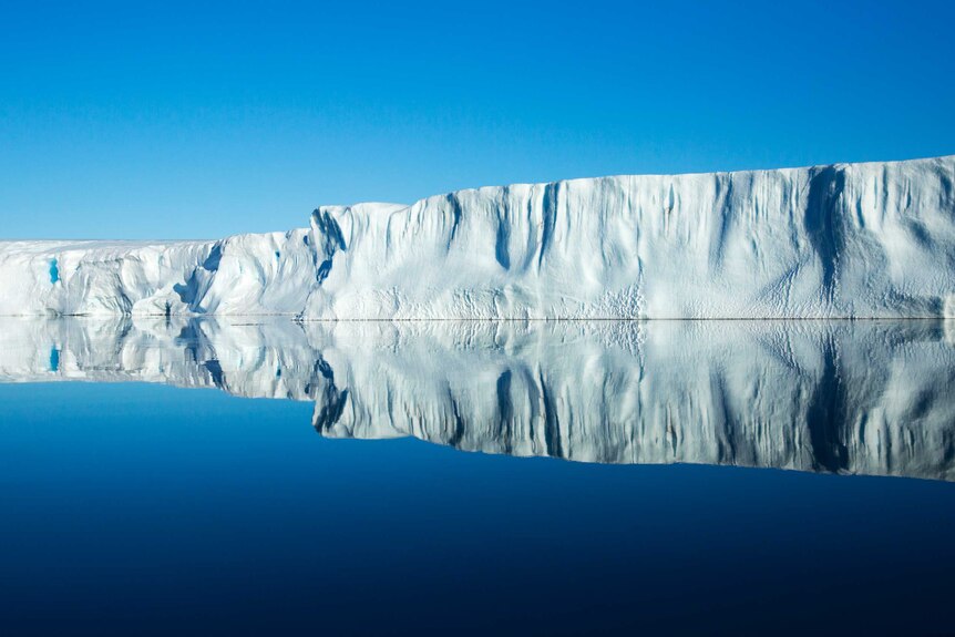 An ice shelf reflected in still water.
