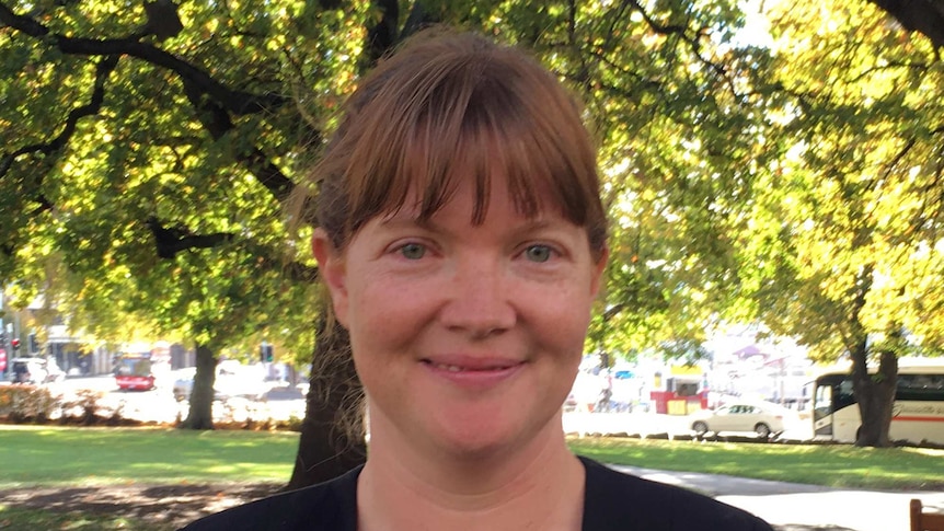 Sarah Lovell smiles and stands in front of trees.