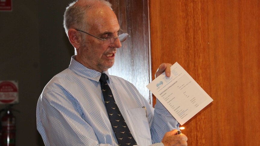 Voluntary euthanasia advocate Philip Nitschke hold a cigarette lighter flame to his medical certificate.