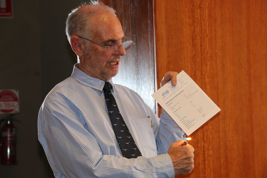 Voluntary euthanasia advocate Philip Nitschke hold a cigarette lighter flame to his medical certificate.