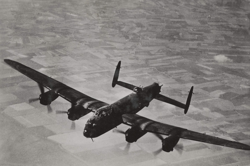 Large WWII bomber aircraft flying over a patchwork of fields below.