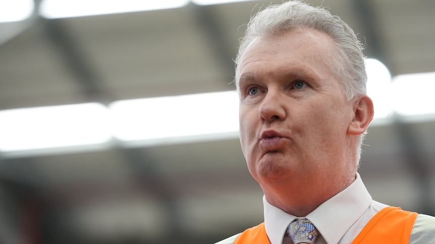 Burke speaks while wearing a high-visibility vest.